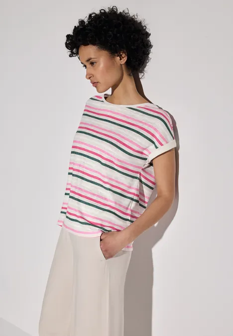 Frau mit lockigem Haar trägt ein gestreiftes Shirt in Rosa und Grün.
